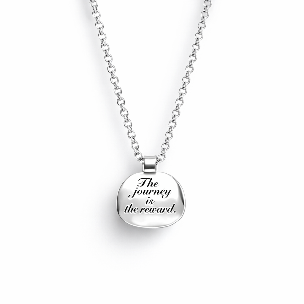 Silver necklace with a pendant that says 'The journey is the reward' on a white background