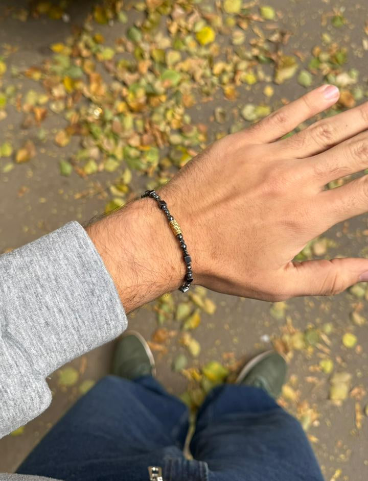 Person wearing a bracelet with leaves on the ground